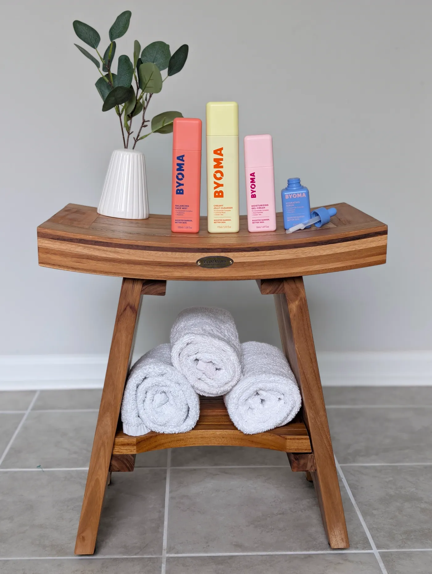 Skincare products styled on a teak bathroom bench
